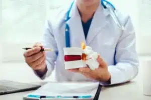 Médica segurando objeto que representa um disco intervertebral e apontando com caneta