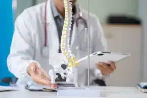 Especialista analisa um modelo de coluna vertebral mostrando os passos de um paciente submetido a cirurgia de reposição espinhal.