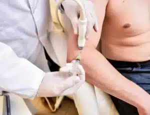 Médico realizando infiltração no cotovelo de um paciente para o tratamento da epicondilite lateral.