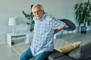 Um senhor de idade sentindo dor na coluna.